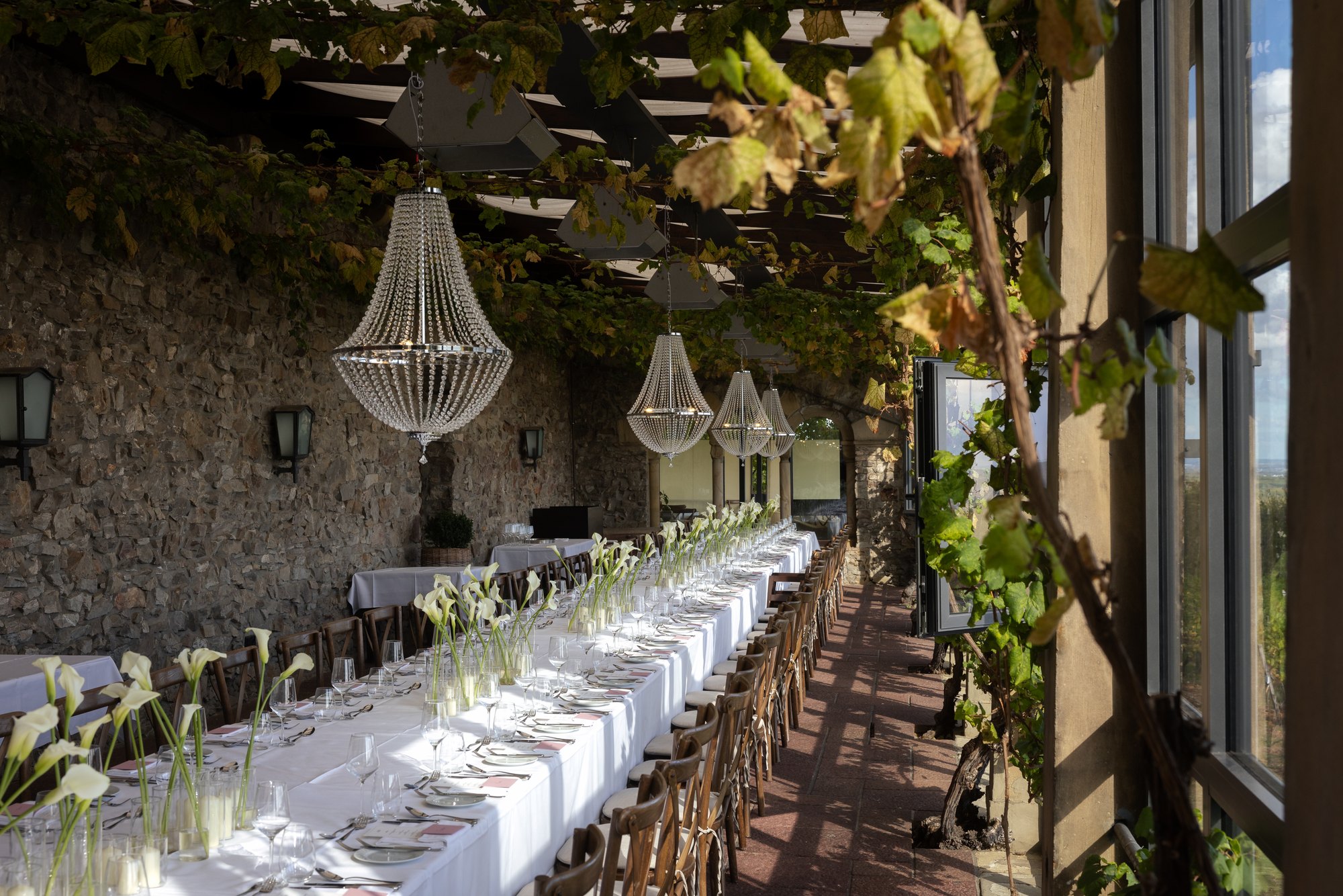 Tafel mit Calla und Kronleuchtern vor der Burgmauer