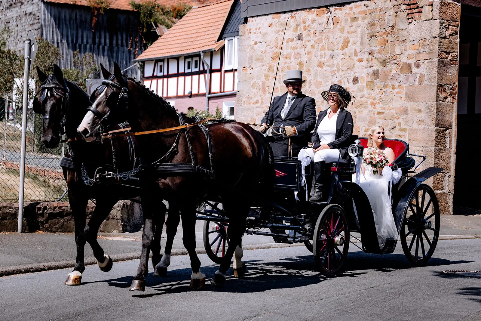 Brautpaar fährt in der Hochzeitskutsche mit zwei Pferden zur Dammühle in Marburg