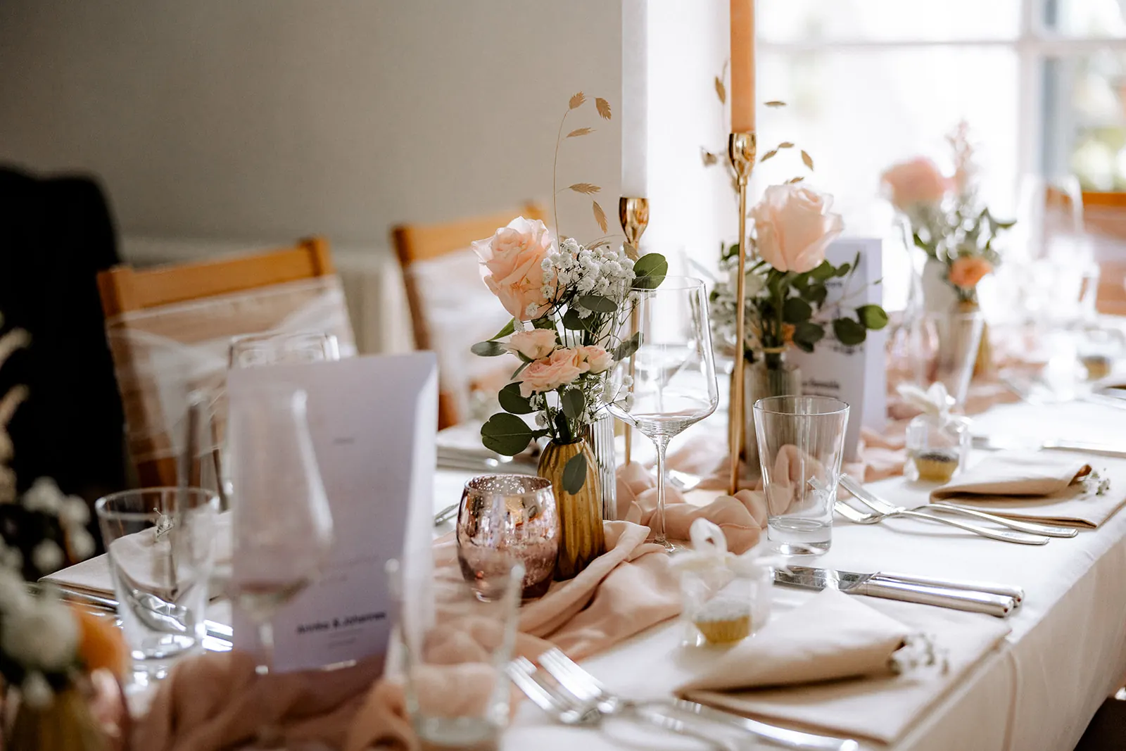 Blumen, Kerzen und Menükarten auf der Hochzeitstafel