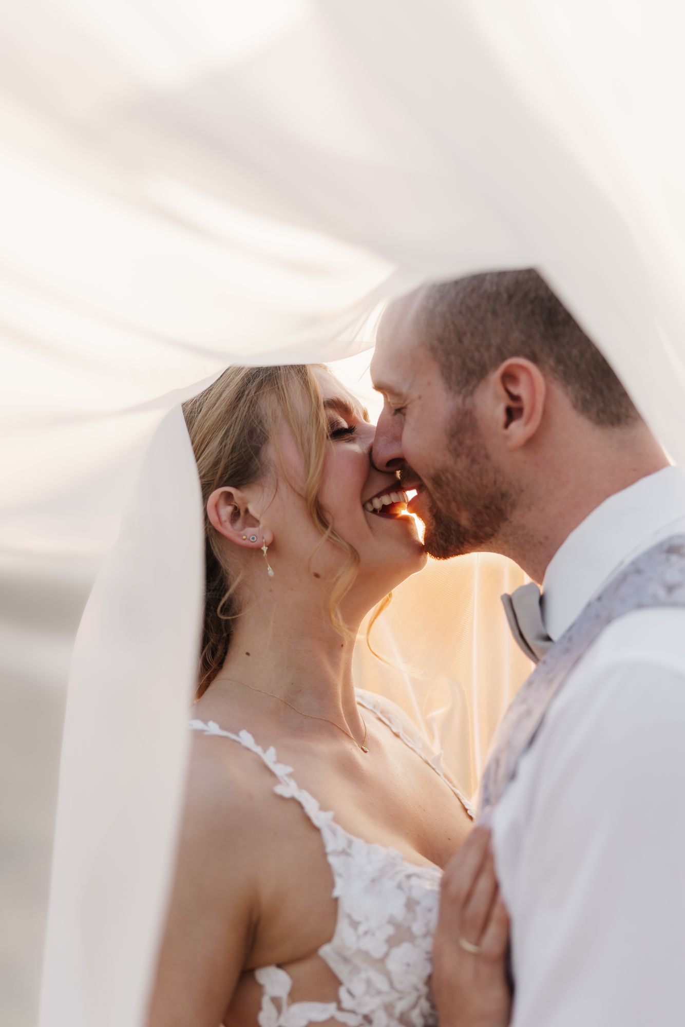 Couple kissing under the veil in golden evening light