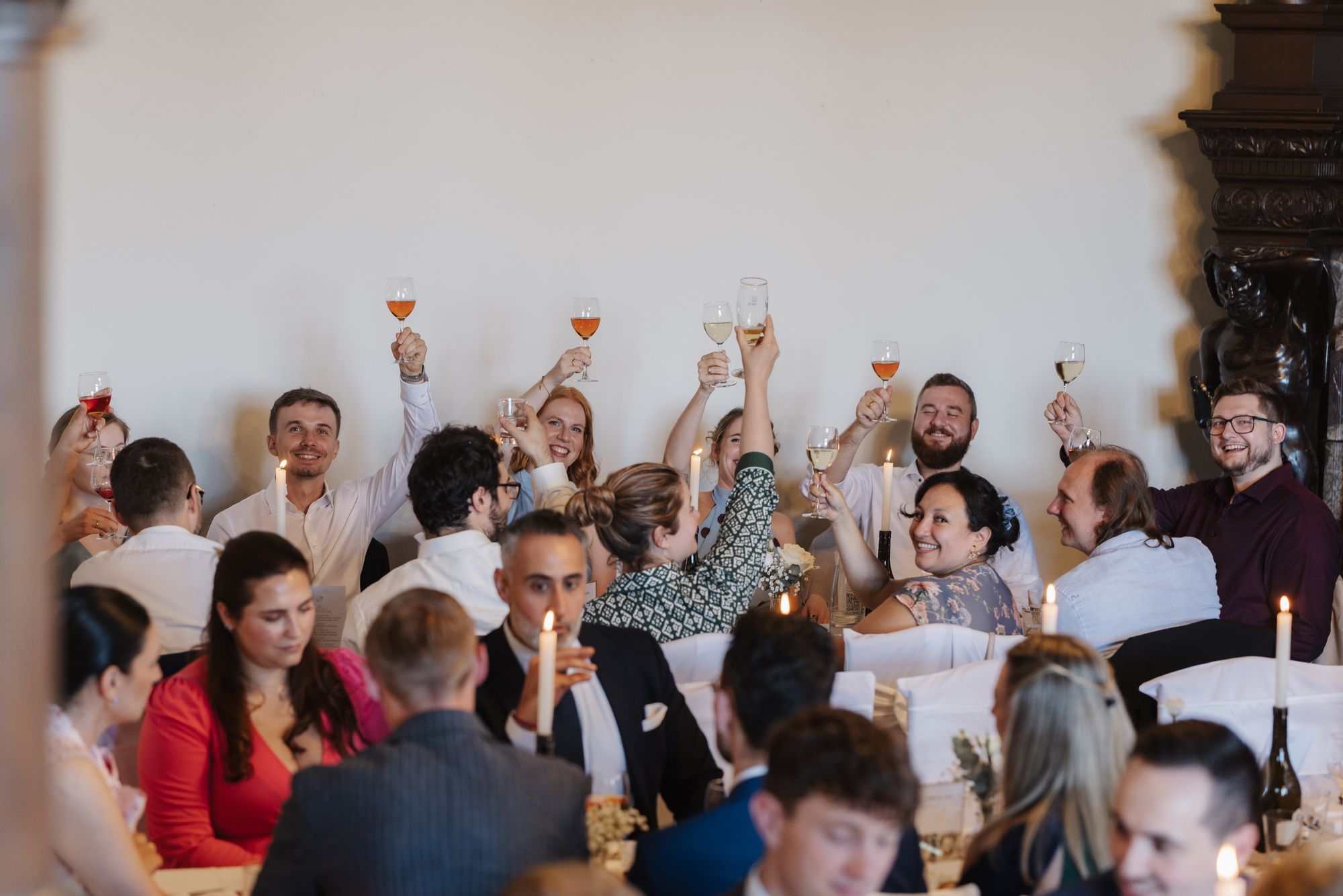 Wedding guests raising their glasses in the hall of Schloss Rauischholzhausen
