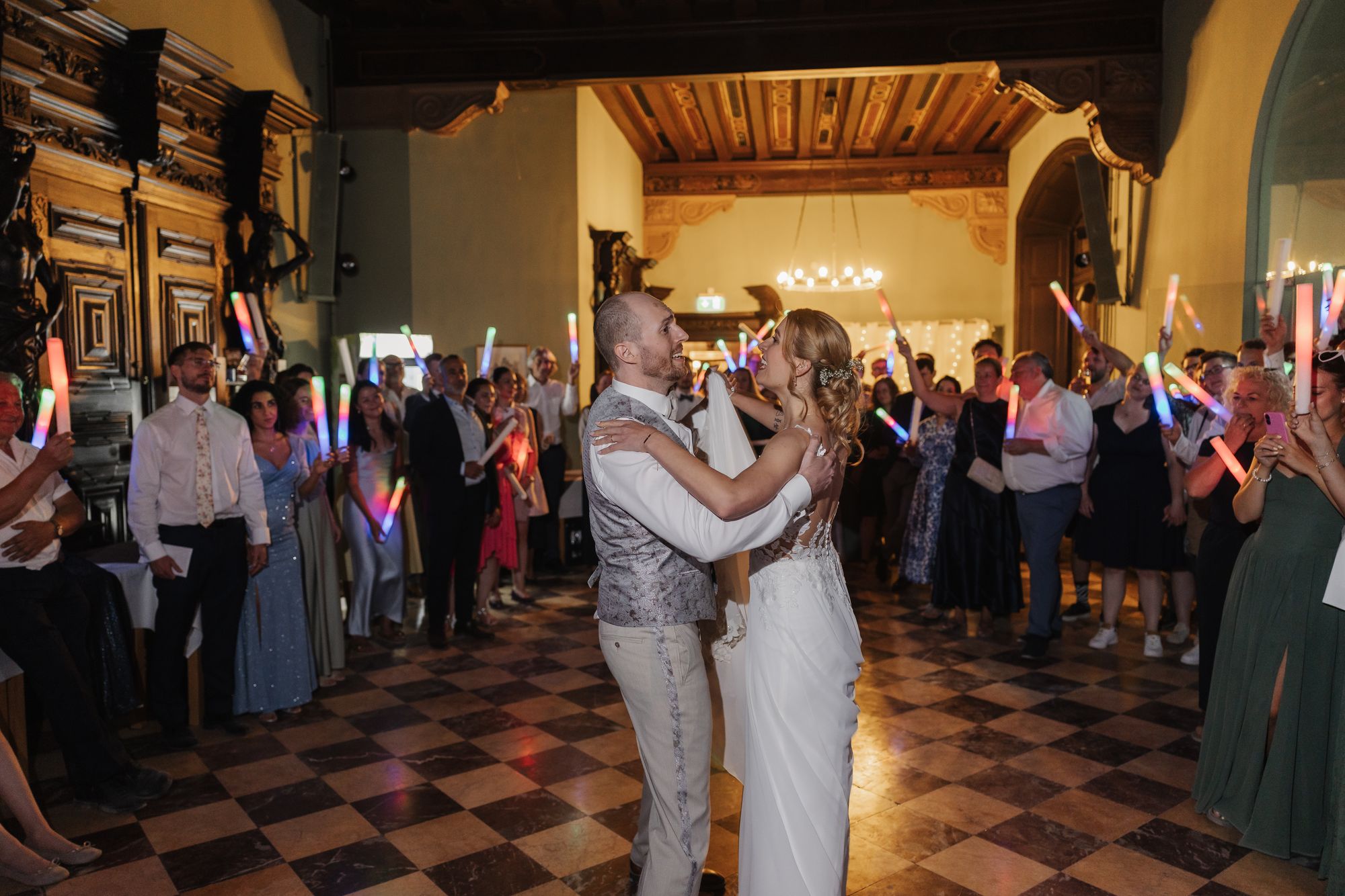 First dance in the hall with guests holding glow sticks in a circle