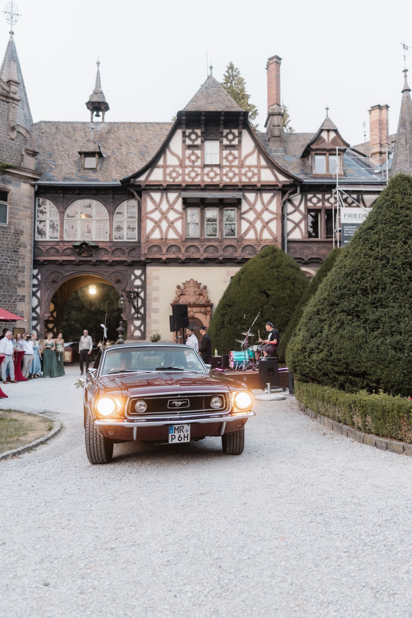 Red vintage Mustang in the courtyard of Schloss Rauischholzhausen in front of the half timbered buildings