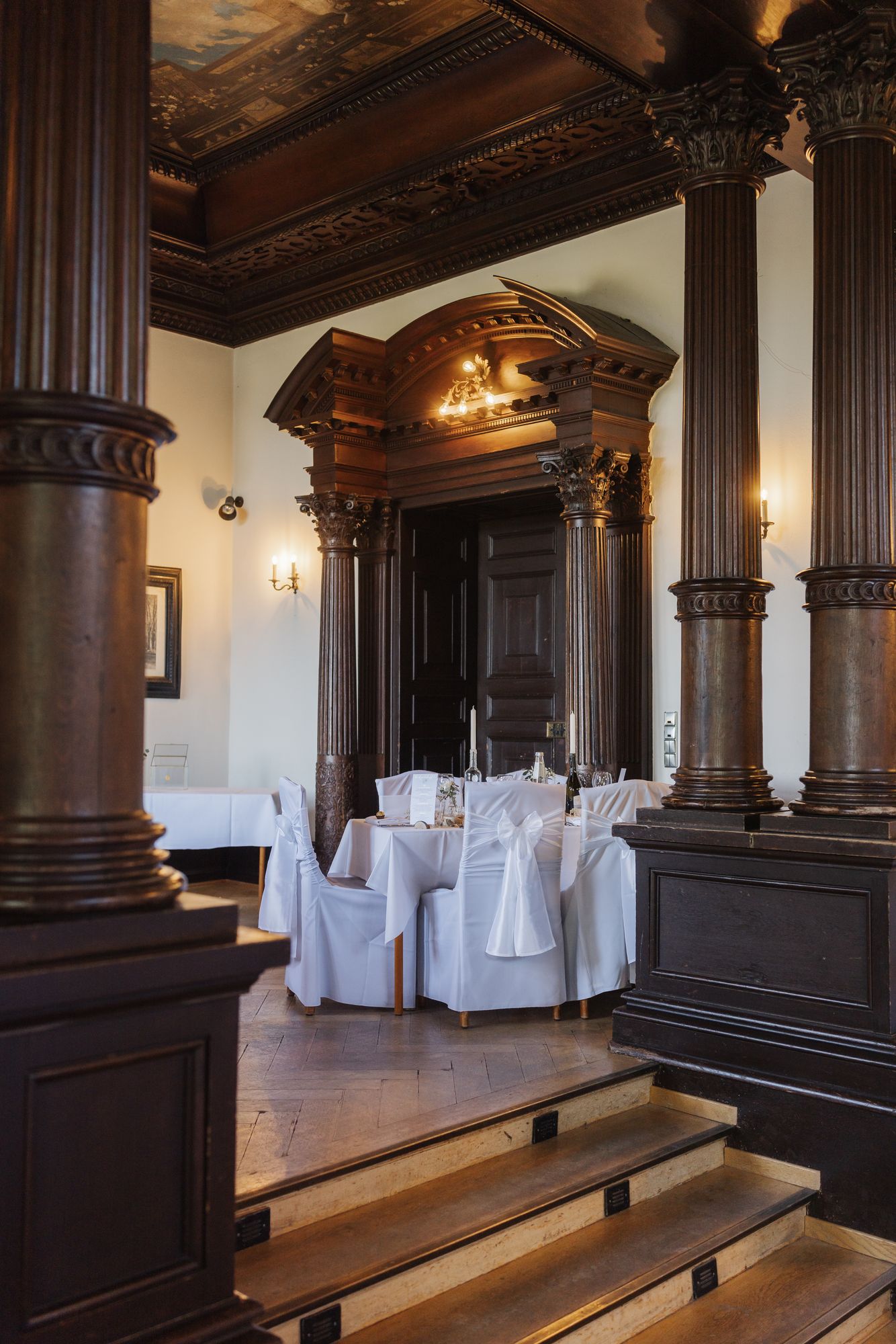 Banquet hall with wooden columns and set tables at Schloss Rauischholzhausen