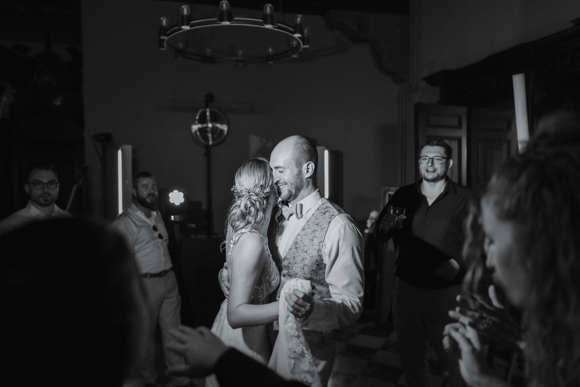 Couple dancing and laughing among their guests, black and white